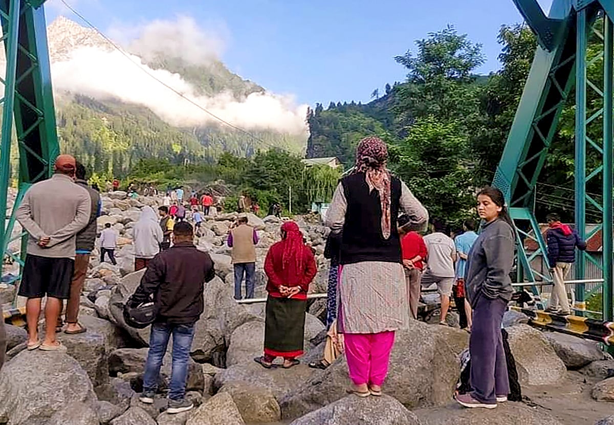 PTI : People stand near debris after flash floods triggered by cloud burst, near Manali, Thursday, July 25